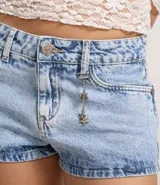 Short de jeans de tiro bajo, color celeste claro desgastado, con trabilla, cierre tradicional y bolsillos. Incluye una cadena decorativa con dijes de estrellas.