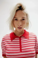 Remera polo de punto fino suave, a rayas horizontales rojas y blancas. Modelo entallado de manga corta con cuello y tapeta de botones.