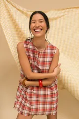 Vestido corto sin mangas con estampado de cuadros en tonos azul, rojo, verde y blanco. Tiene cuello redondo y ruedo con flecos.