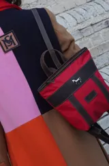 Mochila pequeña color borgoña con detalles en cuero marrón, asa de mano y correas ajustables.
