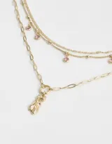 Collar dorado de múltiples cadenas con dije de zapatillas de ballet y strass rosados.