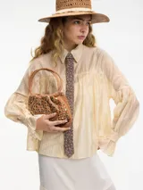 Camisa color crema bordada con botones en la parte delantera, mangas largas con media manga abullonada y cuello camisero.
