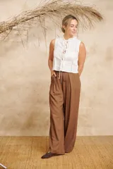 Pantalón ancho color beige de lino con cinto y pretina con elástico en la parte de atrás.
