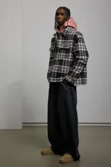 Sobrecamisa de franela de algodón a cuadros blancos, negros y grises. Corte oversized, cuello inglés, tapeta con botones a presión, canesú en la espalda, bolsillos superiores con solapa y botón a presión, bolsillos laterales y bajo recto con aberturas laterales. Mangas largas con tapeta y botón a presión en los puños. Forro guateado.