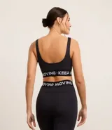 Top deportivo negro de microfibra con breteles anchos, copas desmontables, recorte cut-out en el busto y banda elástica con estampado de letras "Keep Moving".
