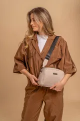 Bandolera pequeña de textura símil cuero color caramelo/marrón, con dos compartimentos principales con cierre. Correa ancha ajustable de tela negra con inscripción en relieve.