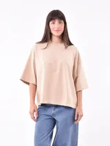 Remera color beige de corte holgado y mangas cortas.