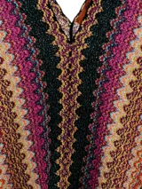 Poncho de tejido de punto con cuello en V y diseño de zigzag multicolor, con flecos largos en el ruedo.