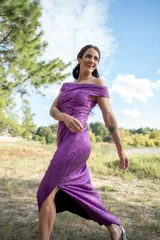 Vestido midi color violeta con textura brillante, escote off-shoulder y mangas cortas.