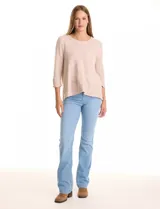 Buzo de tejido suave color beige, con cuello a la base y mangas 3/4 con aplique de botones dorados. Presenta terminación con tajos en los laterales.