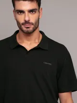 Chomba negra de algodón con textura de crepé, corte regular, manga corta y cuello abierto. Logo de Calvin Klein bordado en el pecho.