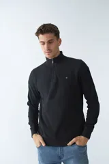 Buzo negro de algodón con cuello alto y medio cierre. Tiene logo bordado en el pecho y puños en las mangas.