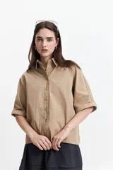 Camisa color beige de corte oversize y manga corta.