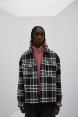 Sobrecamisa de franela de algodón a cuadros blancos, negros y grises. Corte oversized, cuello inglés, tapeta con botones a presión, canesú en la espalda, bolsillos superiores con solapa y botón a presión, bolsillos laterales y bajo recto con aberturas laterales. Mangas largas con tapeta y botón a presión en los puños. Forro guateado.