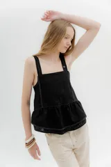 Musculosa negra de lino con tirantes anchos, escote cuadrado, detalle de volantes en el ruedo y elástico en la espalda.