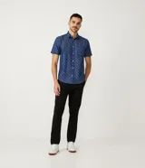 Camisa de manga corta azul con estampado de círculos blancos, cuello camisero, abotonada al frente y con bolsillo en el pecho.
