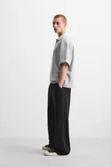 Pantalón jogger negro de corte ancho, confeccionado en tejido de algodón con interior de rizo. Cuenta con cintura elástica ajustable con cordón interior, bolsillos laterales y bolsillo trasero de parche.