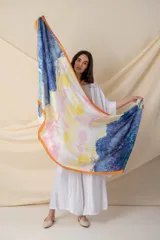 Pañuelo cuadrado de seda con estampado abstracto en degrade de colores azul, amarillo, blanco y rosa, con borde naranja.