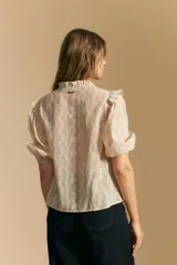 Camisa de manga corta abullonada con terminación elastizada, cuello con leve frunce y calce recto. Presenta una estampa floral integral sobre fondo claro.