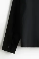 Sobrecamisa negra de manga larga con cuello inglés, tapeta lisa, canesú en la espalda y bolsillo superior de parche.