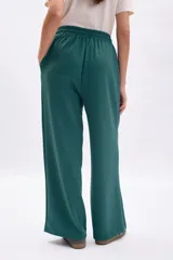Pantalón deportivo ancho de color verde oscuro, con vivo blanco vertical en el centro de cada pierna. Presenta cordón de ajuste en la cintura y corte holgado.