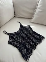 Blusa negra con breteles regulables y apliques de lentejuelas plateadas.