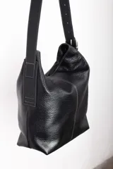 Bolso tipo tote de cuero gamuzado color marrón, con correa de hombro de cuero negro y hebilla metálica. Diseño minimalista y funcional. Confeccionado a mano en Uruguay.