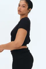 Pantalón negro de punto suave, con cintura ancha plegable y corte acampanado.