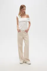 Pantalón jean color beige, de corte recto y holgado, con cintura alta y diseño color block en la parte superior.