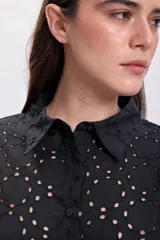 Camisa negra de manga larga con cuello clásico y cierre con botones. Presenta bordado tipo broderie con calados circulares. Corte recto.