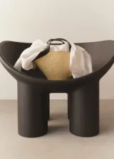 Bolso tipo tote de paja color beige con detalles en cuero sintético negro. Tiene doble asa de mano y correa larga al hombro.