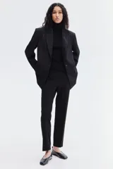 Pantalón cigarette negro de punto elástico pesado con pliegues. Modelo de tiro alto con elástico oculto en la cintura y pinzas adelante y atrás.