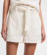 Short de tiro alto color crema, con trabillas en la cintura, cinturón de tela para lazo, elástico en la espalda, cierre por cremallera y detalles de lentejuelas bordadas.