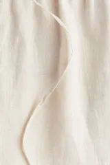Pantalón de lino color crema, de corte holgado, con cintura elastizada y cordón de ajuste.