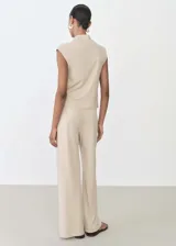 Pantalón largo de mujer color beige, de corte ancho y tiro alto, con cintura elástica y lazo ajustable.