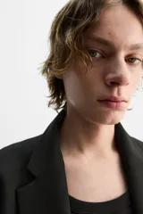 Blazer negro de corte regular fit, confeccionado en tejido con viscosa. Presenta cuello con solapas de muesca, manga larga con puños abotonados, bolsillo de vivo en el pecho, bolsillos de solapa en la cadera, bolsillo interior, aberturas en la espalda y cierre frontal con dos botones.