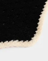 Pañuelo tejido negro con borde a contratono color crema.