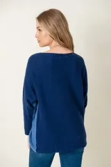 Sweater de lana gris claro con mangas largas y corte holgado. Presenta una franja vertical gris oscuro a lo largo de cada manga.