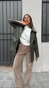 Chaqueta color marrón con cuello de piel sintética, cierre frontal con cremallera, bolsillos laterales con solapa y corte recto.