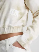Buzo corto de algodón color blanco con estampado tie dye en tonos beige, cuello redondo, mangas largas, bajo elástico y parche con el monograma de Calvin Klein en el pecho.