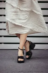 Sandalias de plataforma color blanco, con tiras cruzadas sobre el empeine, pulsera al tobillo con hebilla dorada y taco ancho.