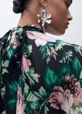 Blusa de gasa con estampado floral, cuello alto, manga larga con volantes y cierre de lazo en la parte posterior.
