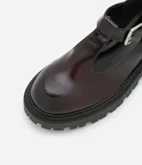 Zapato Mary Jane color borgoña de charol, con punta redonda, cierre con hebilla lateral y suela track.