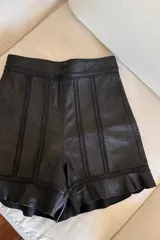 Short de cuero ovino negro con bordados y volados en el ruedo.