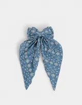 Hebilla francesa para el pelo con moño grande de tela celeste con bordado de flores blancas.