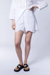 Short blanco con bordado calado tipo broderie, cintura elastizada y ruedo con volados.