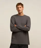 Remera gris de corte relaxed, cuello redondo y manga larga. Tiene un pequeño estampado central.