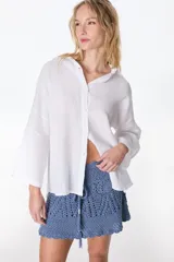 Camisa de lino color blanco, de manga larga y corte holgado, con cuello camisero y cierre frontal de botones.