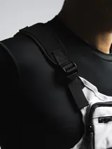 Bolso de pecho táctico color gris claro con detalles en negro. Posee un compartimento principal con cierre y correas ajustables negras para llevar cruzado sobre el pecho.