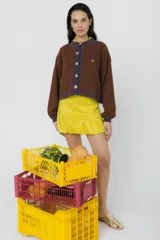 Cárdigan marrón de punto con bordes acanalados en azul y cierre frontal con botones. Tiene bordado un limón en el pecho.